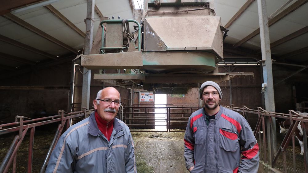 Florian Studer (à droite) prend la pose avec Pascal Comte sous la pailleuse suspendue dans la stabulation des 75 vaches laitières du Gaec du Rocheret.  