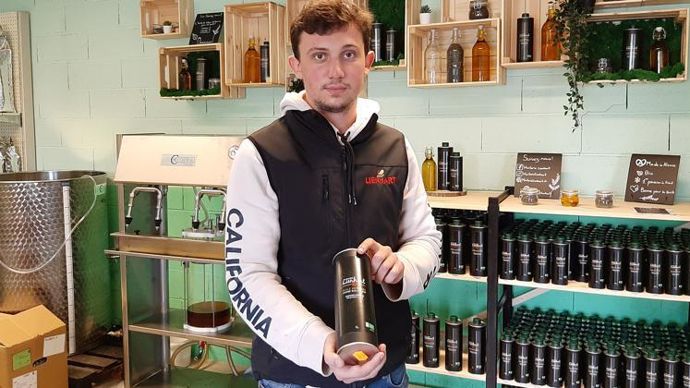Geoffrey Lienhart présente une bouteille d’un litre devant l’atelier de conditionnement artisanal installé dans le point de vente. © C. REIBEL