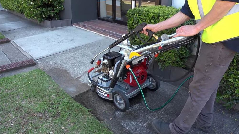 La machine possède à la fois une lance à haute pression et une rampe rotative pour nettoyer le sol.