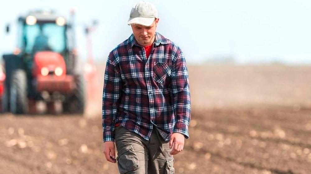 Agriculteur triste dans un champ avec un tracteur