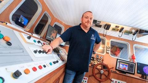 Le visiteur est invité à tenir la barre dans un navire reconstitué, ici avec Sébastien, ancien marin et guide.